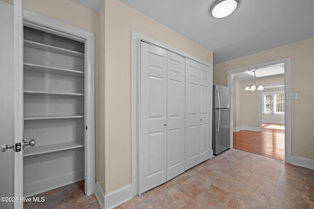 unfurnished bedroom featuring an inviting chandelier and stainless steel fridge