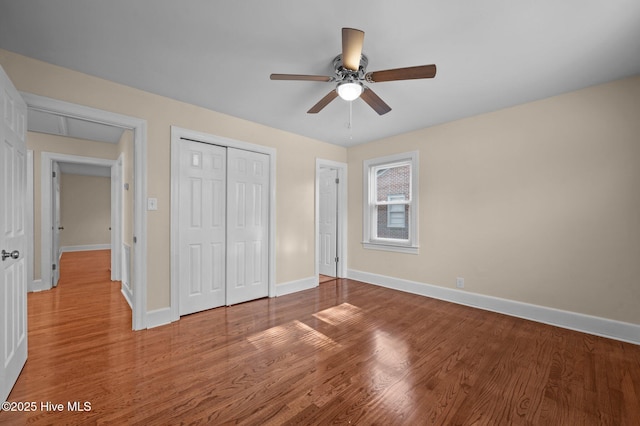 unfurnished bedroom featuring hardwood / wood-style flooring, ceiling fan, and a closet