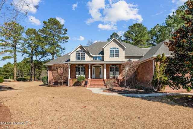 view of front of house featuring a porch, crawl space, a shingled roof, and brick siding