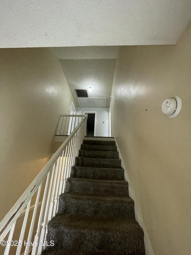 stairway featuring a textured ceiling