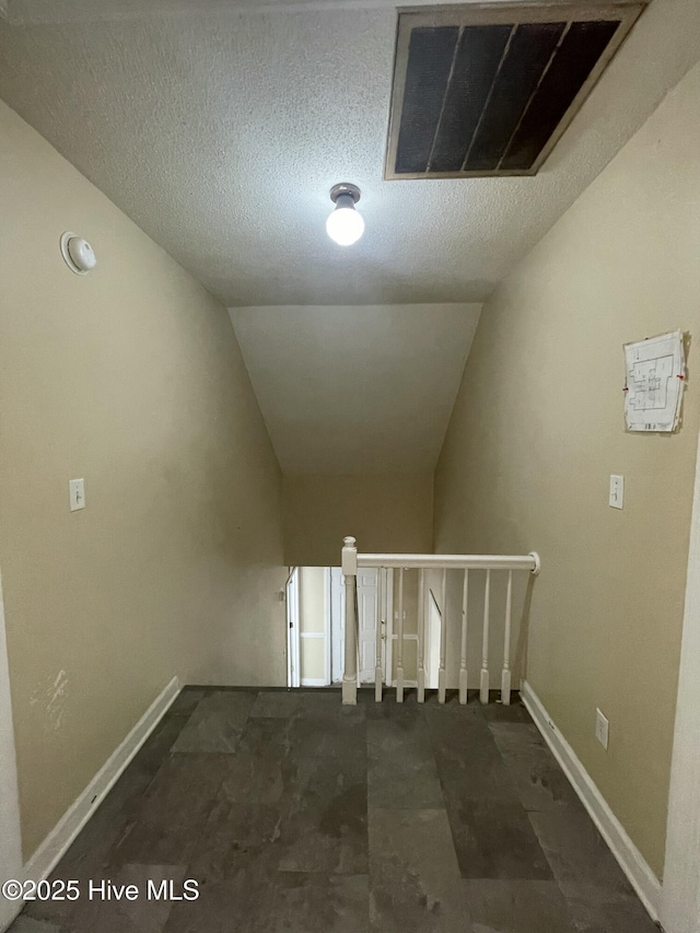 hallway featuring a textured ceiling and vaulted ceiling