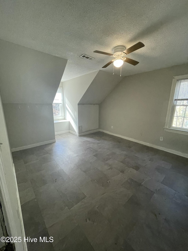 bonus room with ceiling fan, plenty of natural light, a textured ceiling, and lofted ceiling