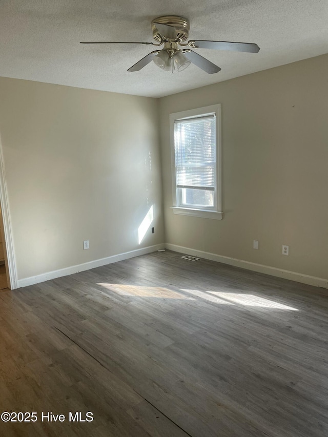 empty room with ceiling fan, dark hardwood / wood-style flooring, and a textured ceiling