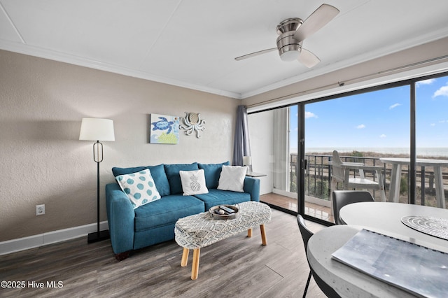 living room featuring a textured wall, wood finished floors, a ceiling fan, baseboards, and ornamental molding