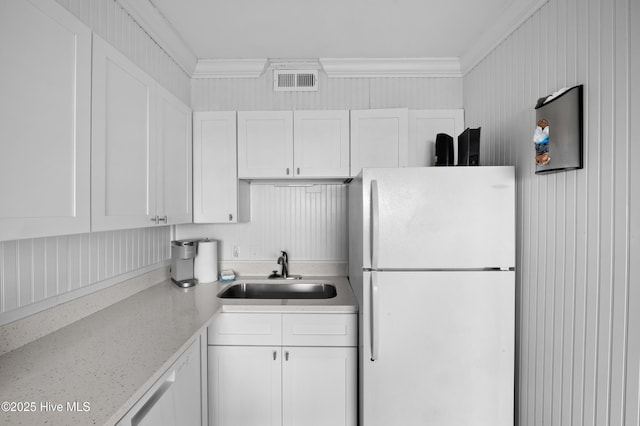 kitchen featuring white appliances, white cabinetry, light stone counters, and a sink