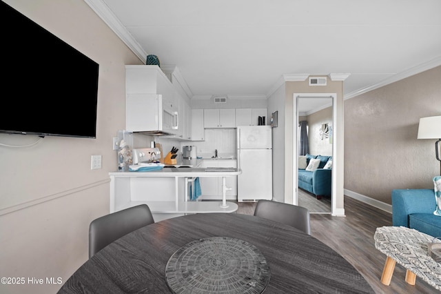 kitchen featuring visible vents, white cabinets, light countertops, freestanding refrigerator, and crown molding