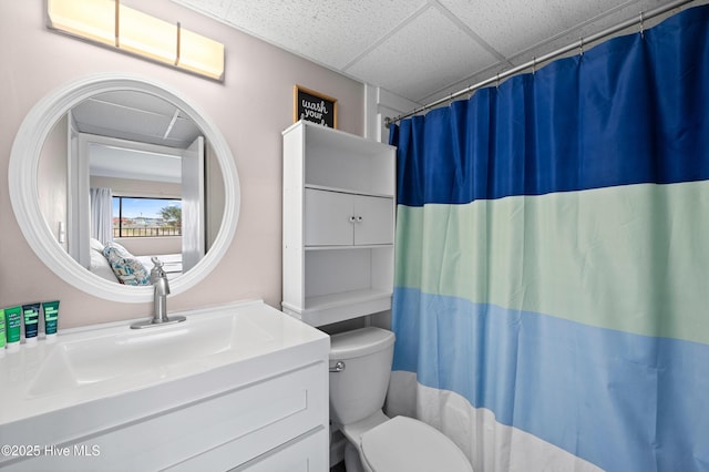 bathroom featuring curtained shower, a drop ceiling, vanity, and toilet