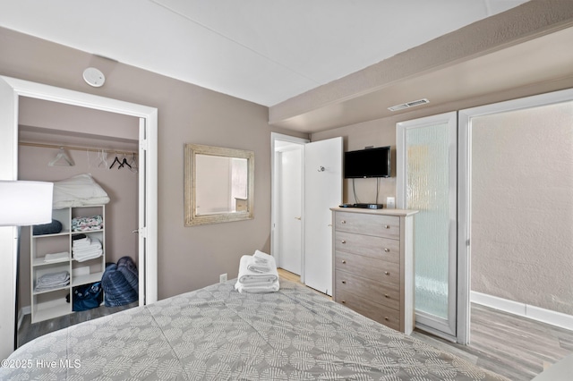 bedroom with light wood-style flooring, visible vents, and a closet