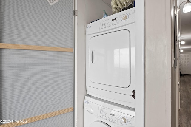 clothes washing area with stacked washing maching and dryer and laundry area