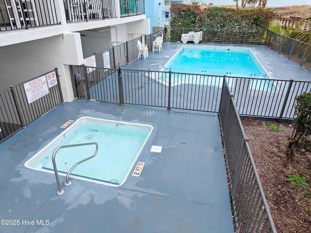 view of swimming pool featuring a hot tub and fence