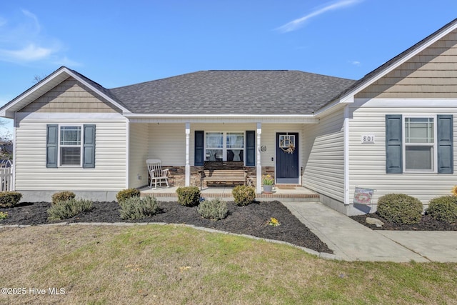 view of front of property featuring covered porch, a shingled roof, and a front yard