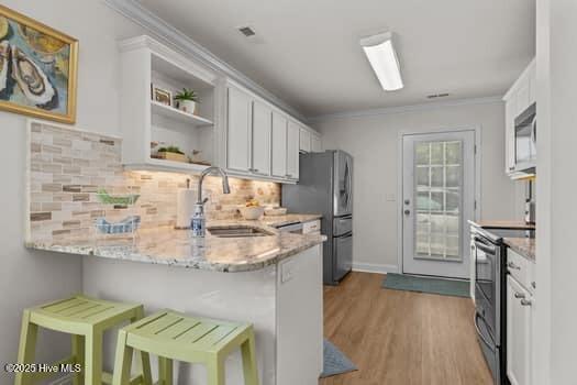 2011 Fisher St, Morehead City, NC 28557 - kitchen with appliances with stainless steel finishes, white cabinetry, tasteful backsplash, light stone countertops, and open shelves