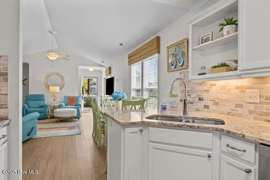 2011 Fisher St, Morehead City, NC 28557 - kitchen featuring open floor plan, vaulted ceiling, white cabinetry, and decorative backsplash