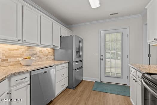 2011 Fisher St, Morehead City, NC 28557 - kitchen featuring appliances with stainless steel finishes, crown molding, white cabinetry, light wood-style floors, and decorative backsplash