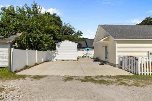 2011 Fisher St, Morehead City, NC 28557 - view of side of home featuring a storage unit, a patio area, and a fenced backyard