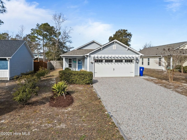 ranch-style house featuring an attached garage, gravel driveway, and fence