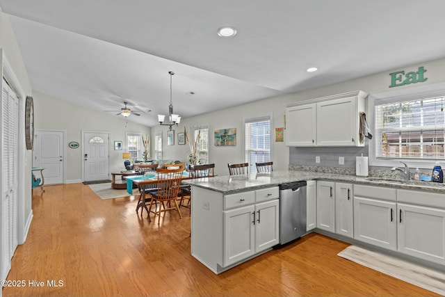 kitchen featuring light wood-style flooring, a peninsula, a sink, white cabinets, and stainless steel dishwasher