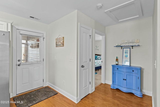 foyer entrance featuring light wood-type flooring, baseboards, and visible vents