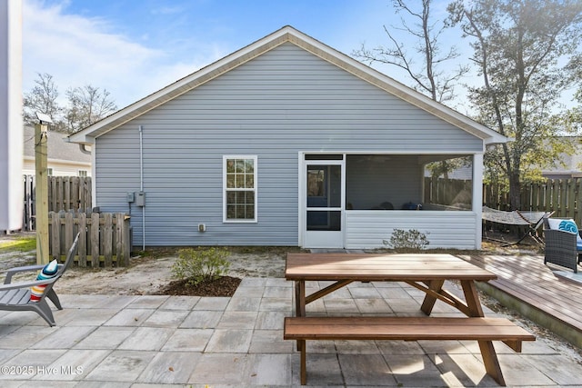 back of property with a patio, a sunroom, fence, a deck, and outdoor dining area