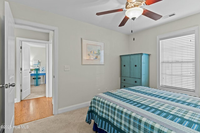 bedroom with baseboards, visible vents, ceiling fan, and light colored carpet