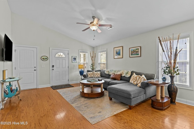 living area featuring wood finished floors, visible vents, a ceiling fan, vaulted ceiling, and baseboards