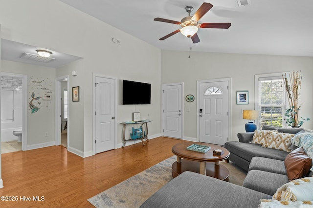 living room with lofted ceiling, visible vents, a ceiling fan, light wood-type flooring, and baseboards