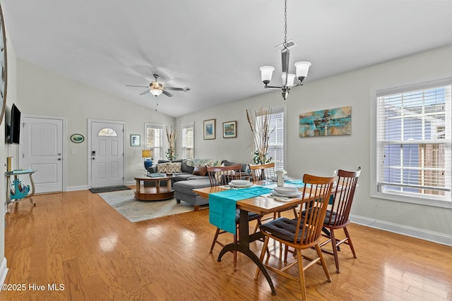 dining room with lofted ceiling, light wood-style floors, plenty of natural light, and ceiling fan with notable chandelier