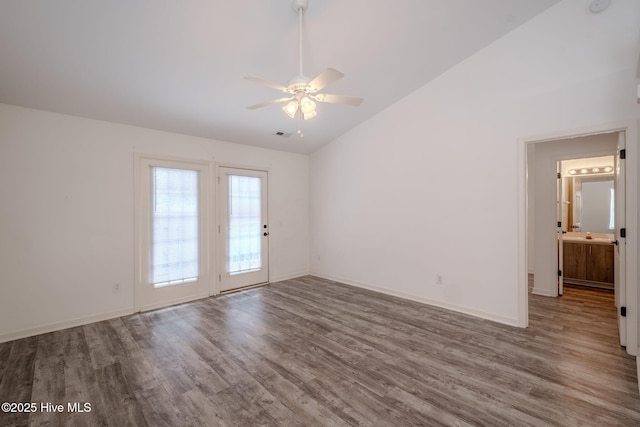 spare room with lofted ceiling, baseboards, and wood finished floors