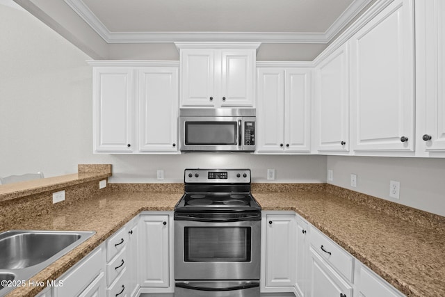 kitchen with appliances with stainless steel finishes, dark stone countertops, crown molding, and white cabinets