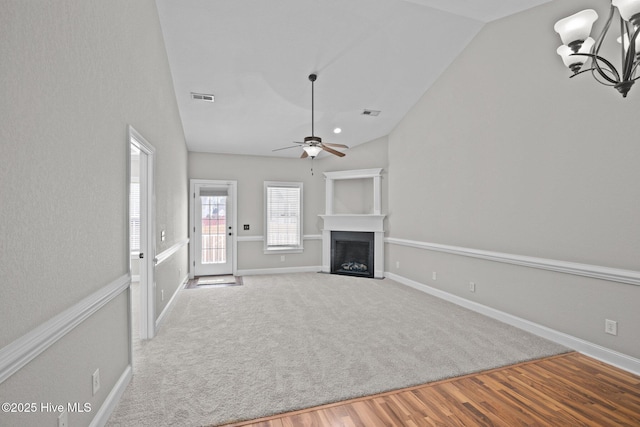 unfurnished living room featuring vaulted ceiling, light hardwood / wood-style floors, and ceiling fan with notable chandelier