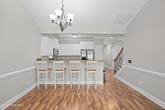 kitchen with a kitchen bar, white cabinetry, pendant lighting, stainless steel appliances, and kitchen peninsula