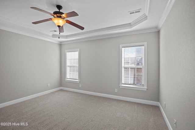 carpeted empty room featuring a raised ceiling, ceiling fan, and crown molding