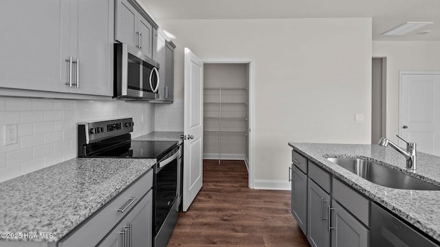 kitchen with stainless steel appliances, light stone counters, decorative backsplash, sink, and dark hardwood / wood-style floors