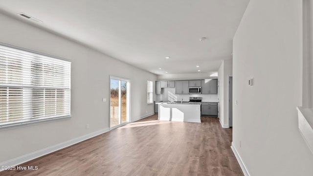 kitchen with gray cabinets, wood-type flooring, and a kitchen island with sink