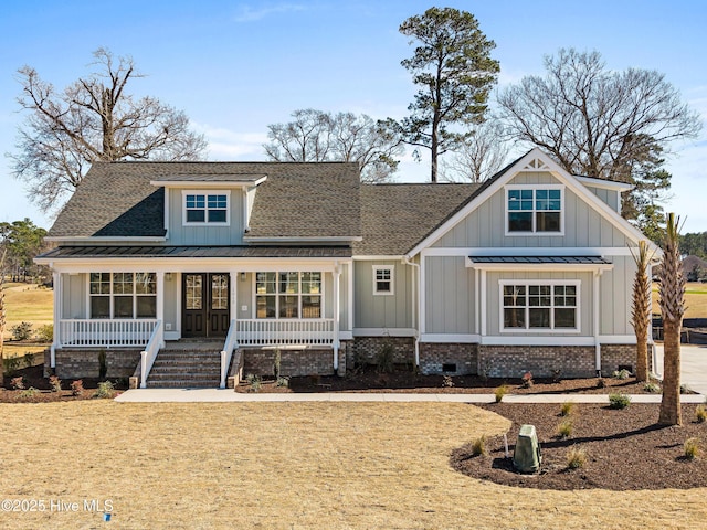 view of front of house with covered porch, french doors, and a front yard