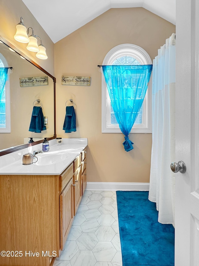 full bathroom with lofted ceiling, baseboards, and vanity