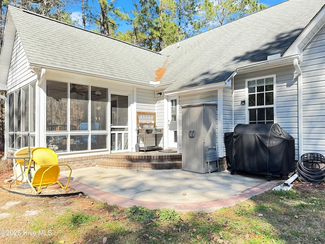 rear view of house with a sunroom, a patio area, and roof with shingles