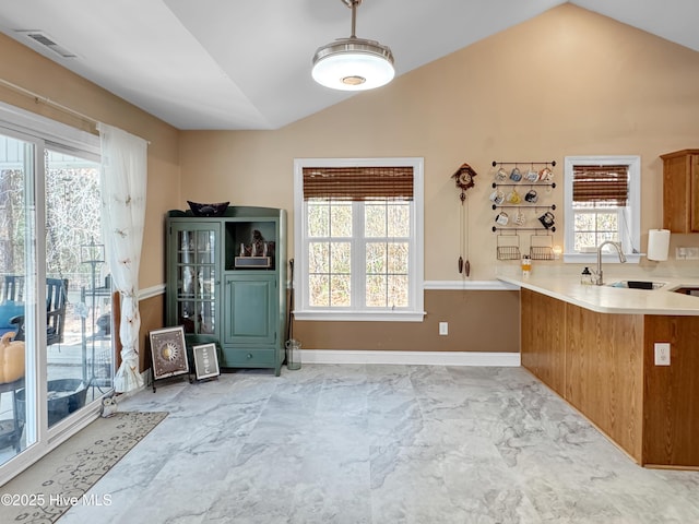 kitchen featuring a peninsula, visible vents, light countertops, and lofted ceiling