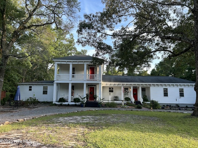 greek revival house with covered porch, a balcony, a front lawn, a shingled roof, and driveway