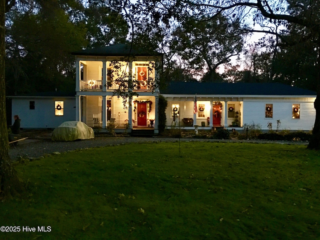 view of front of property with a balcony, a front yard, and covered porch