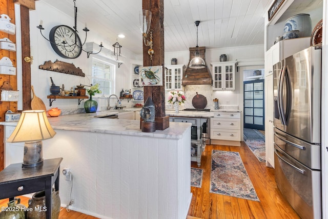 121 Dolphin Ln, Sneads Ferry, NC 28460 - kitchen with appliances with stainless steel finishes, premium range hood, a peninsula, light wood-style flooring, and glass insert cabinets