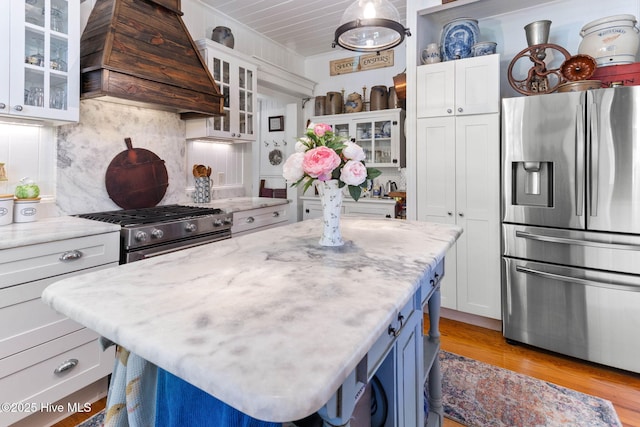 121 Dolphin Ln, Sneads Ferry, NC 28460 - kitchen with appliances with stainless steel finishes, custom exhaust hood, white cabinetry, a kitchen island, and decorative backsplash