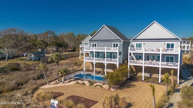 rear view of property featuring an outdoor pool, a fenced backyard, a patio, and a balcony