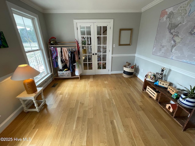 dining area with light wood-type flooring, crown molding, and french doors