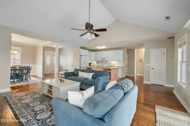 living room with a wainscoted wall, visible vents, wood finished floors, decorative columns, and vaulted ceiling