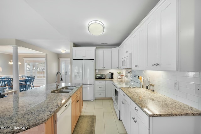 kitchen featuring white appliances, decorative columns, a sink, white cabinets, and tasteful backsplash