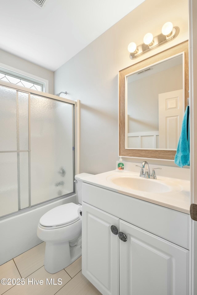 bathroom with tile patterned floors, shower / bath combination with glass door, vanity, and toilet