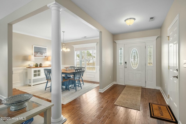 foyer entrance featuring ornate columns, crown molding, and wood-type flooring