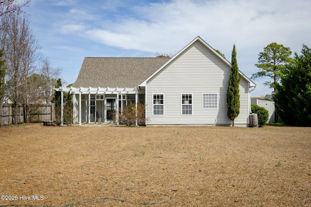 back of property with fence, a pergola, and roof with shingles