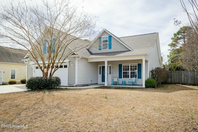 view of front facade featuring roof with shingles, covered porch, an attached garage, and fence